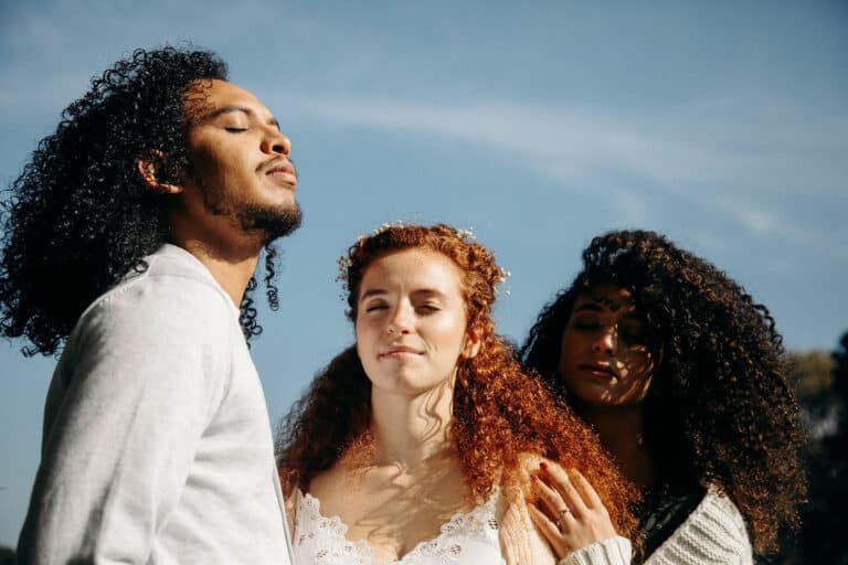 trois personnes se tiennent au soleil : un homme maghrébin, une femme rousse, une femme métisse