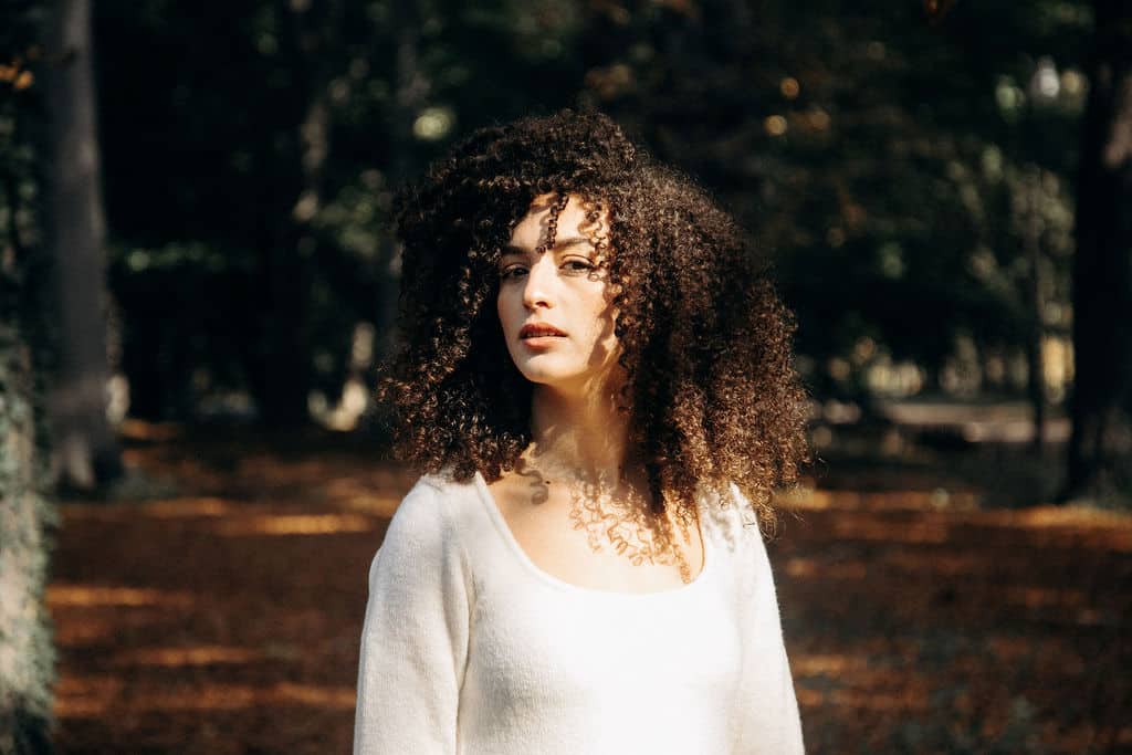 Une femme se tient debout avec ses longs cheveux détachés et frisés.