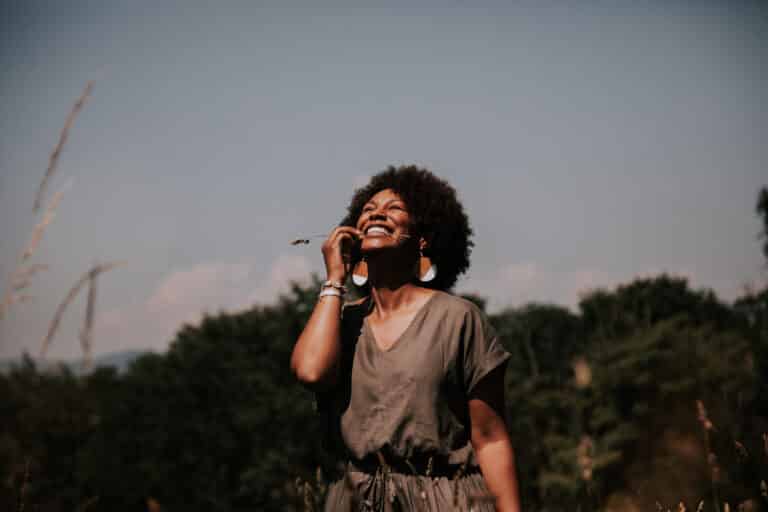 A black woman stands in a field and smiles